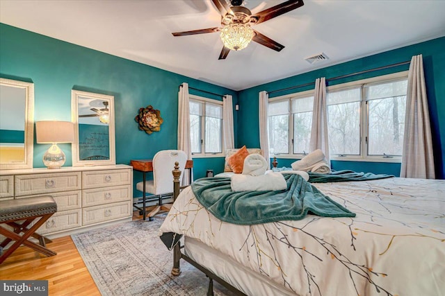 bedroom with baseboard heating, ceiling fan, and light wood-type flooring