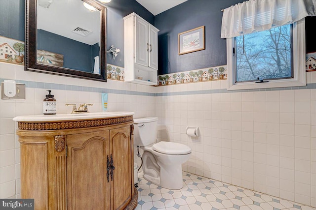 bathroom with vanity, toilet, and tile walls