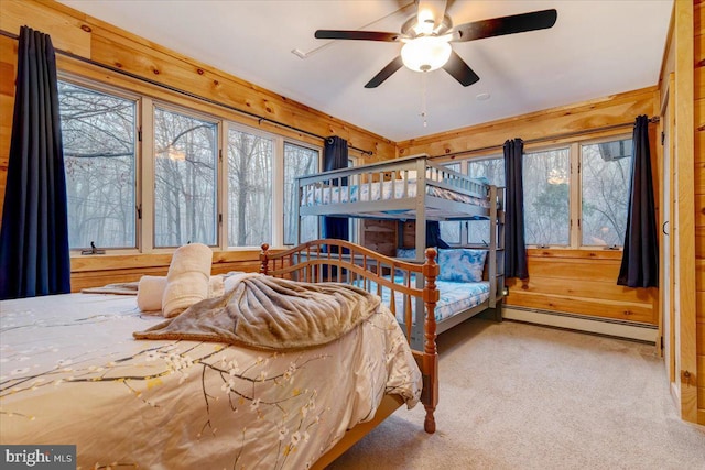 bedroom with a baseboard radiator, wooden walls, light colored carpet, and ceiling fan