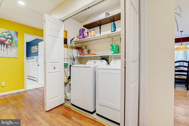 washroom with a baseboard heating unit, washing machine and clothes dryer, and light wood-type flooring