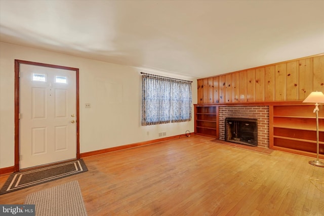 unfurnished living room featuring wood-type flooring, a fireplace, and wood walls