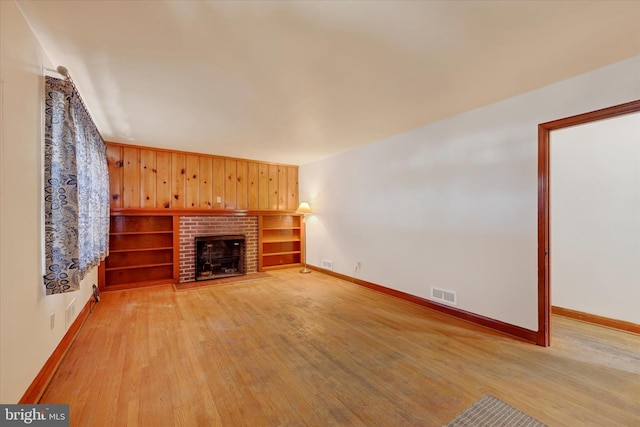 unfurnished living room featuring a fireplace, light hardwood / wood-style floors, and built in features