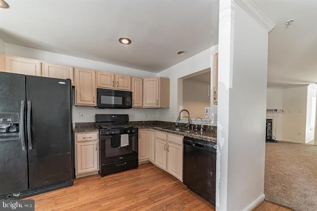 kitchen featuring sink, dark stone counters, black appliances, light brown cabinets, and light hardwood / wood-style flooring