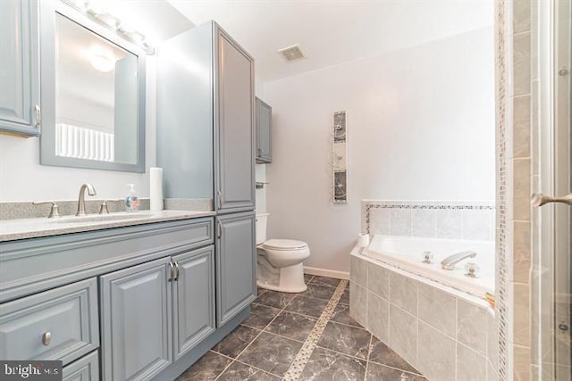 bathroom featuring vanity, a relaxing tiled tub, and toilet