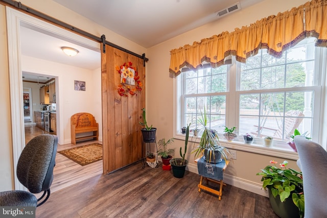 interior space with wood-type flooring and a barn door