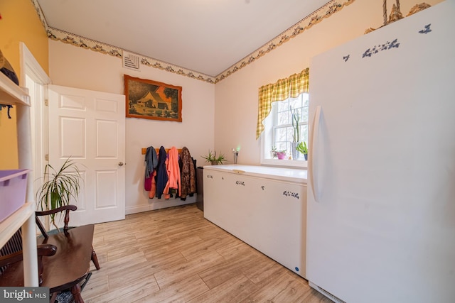 clothes washing area with light hardwood / wood-style floors