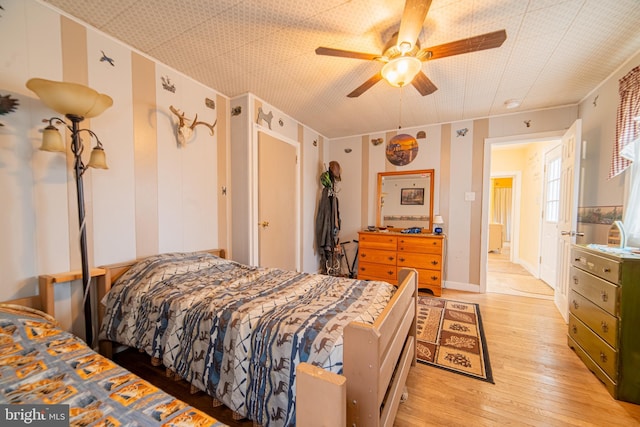 bedroom with light hardwood / wood-style flooring, ornamental molding, and ceiling fan