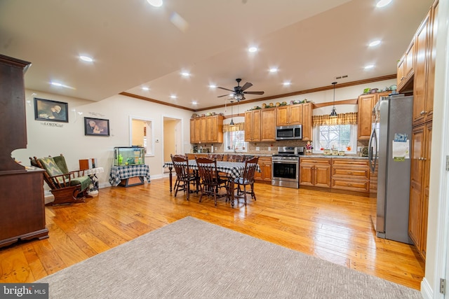 kitchen with appliances with stainless steel finishes, a breakfast bar, hanging light fixtures, a center island, and light hardwood / wood-style floors