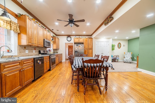 interior space with sink, appliances with stainless steel finishes, light hardwood / wood-style floors, light stone countertops, and decorative light fixtures