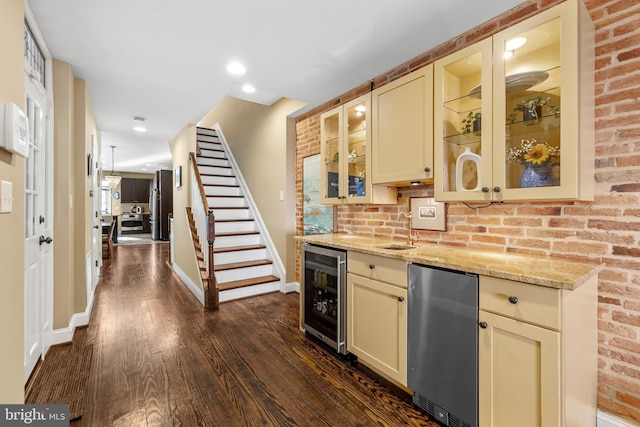 bar featuring dark wood-type flooring, sink, beverage cooler, light stone countertops, and cream cabinetry