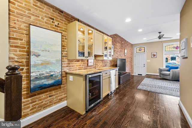 kitchen featuring sink, light stone counters, dark hardwood / wood-style flooring, brick wall, and beverage cooler