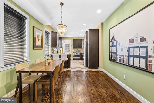 dining space with sink, dark hardwood / wood-style floors, and a chandelier