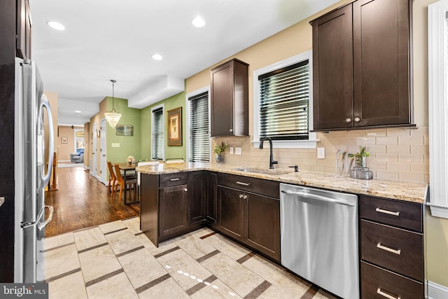 kitchen featuring sink, decorative light fixtures, light tile patterned floors, kitchen peninsula, and stainless steel appliances