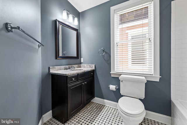 bathroom featuring vanity, toilet, tile patterned flooring, and tiled tub