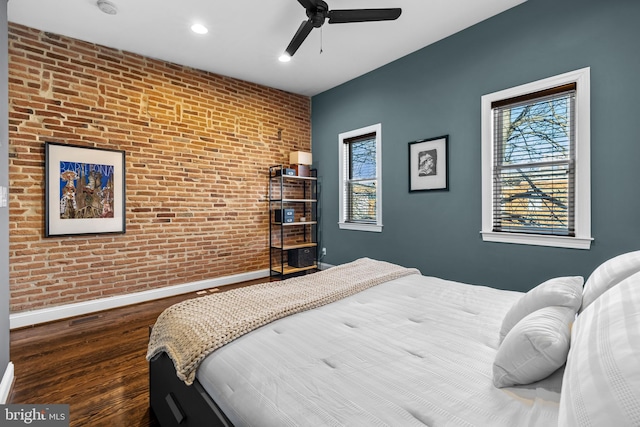 bedroom featuring dark wood-type flooring, ceiling fan, and brick wall