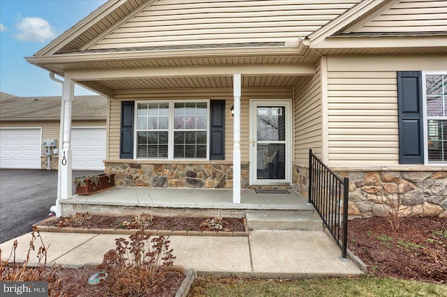 view of exterior entry with a garage and covered porch