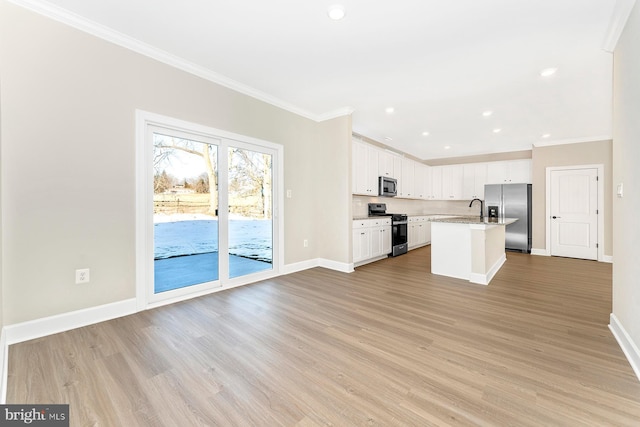 kitchen featuring white cabinetry, ornamental molding, a kitchen island with sink, stainless steel appliances, and light hardwood / wood-style flooring