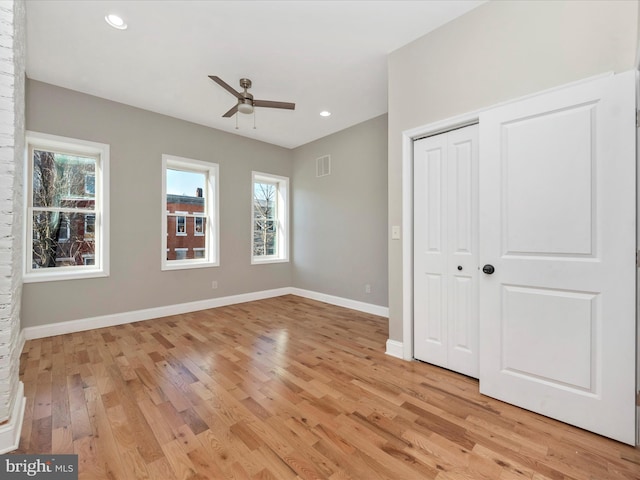 unfurnished bedroom with ceiling fan, multiple windows, and light wood-type flooring