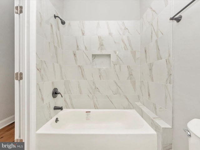 bathroom featuring tiled shower / bath and toilet