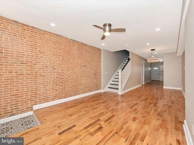 spare room featuring ceiling fan, brick wall, and light hardwood / wood-style floors