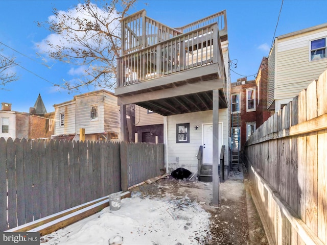 snow covered back of property featuring a balcony