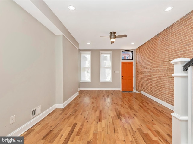 foyer with ceiling fan, brick wall, and light hardwood / wood-style floors