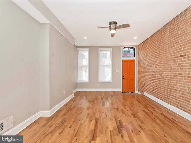 entryway featuring light hardwood / wood-style floors, ceiling fan, and brick wall