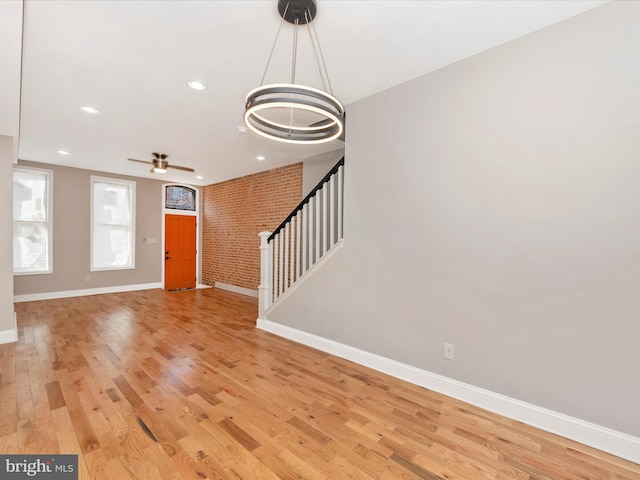 foyer with light hardwood / wood-style flooring, ceiling fan, and brick wall