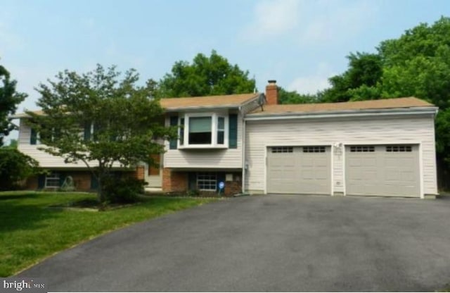 raised ranch featuring a garage and a front yard