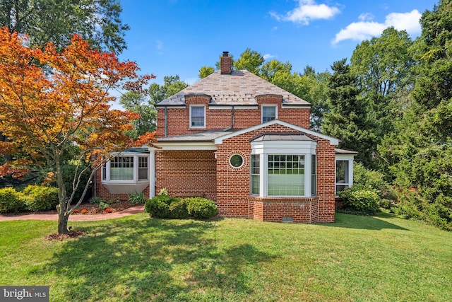 view of front of house featuring a chimney, a front lawn, and brick siding