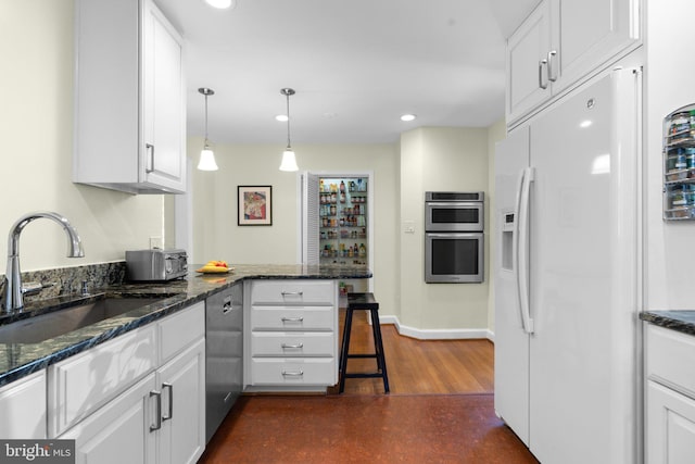 kitchen featuring a peninsula, white cabinets, stainless steel appliances, and a sink