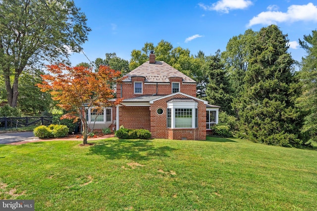 view of front of home featuring a chimney, crawl space, fence, a front lawn, and brick siding