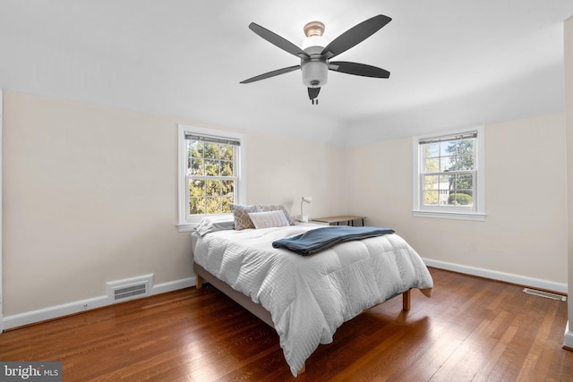 bedroom featuring wood-type flooring, multiple windows, visible vents, and baseboards