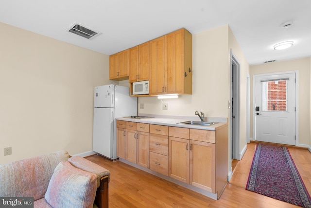 kitchen featuring white appliances, visible vents, light wood finished floors, and a sink