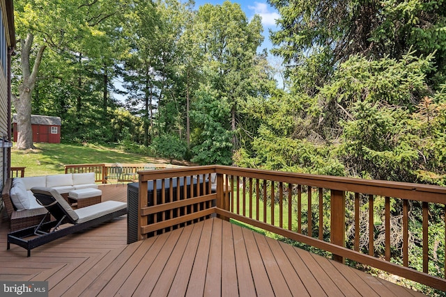 wooden terrace featuring a yard, an outdoor structure, a shed, and an outdoor hangout area