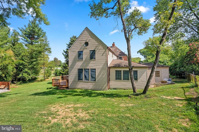 back of house with a yard, a chimney, and a wooden deck