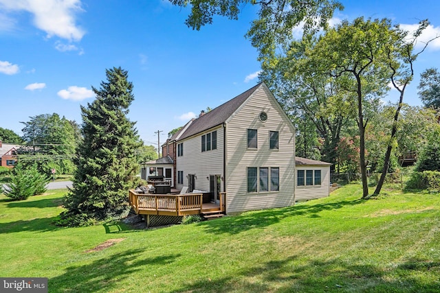 back of property with fence, a wooden deck, and a lawn