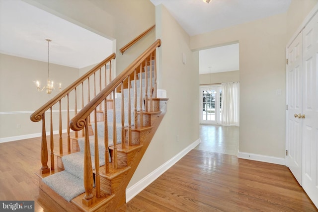 stairs with hardwood / wood-style flooring and a chandelier