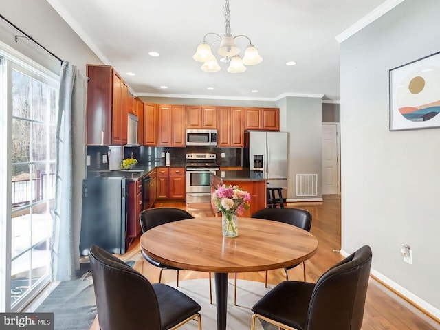 dining area with light hardwood / wood-style flooring, ornamental molding, and a chandelier