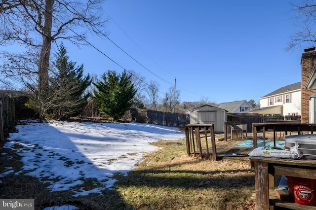 yard layered in snow featuring a shed and a covered pool