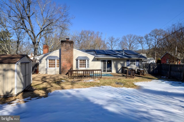 snow covered property featuring a storage unit, a deck, and solar panels