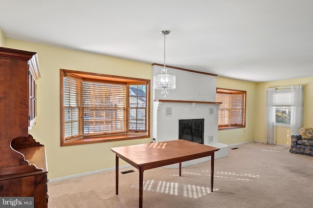 dining space featuring light carpet, a fireplace, and an inviting chandelier