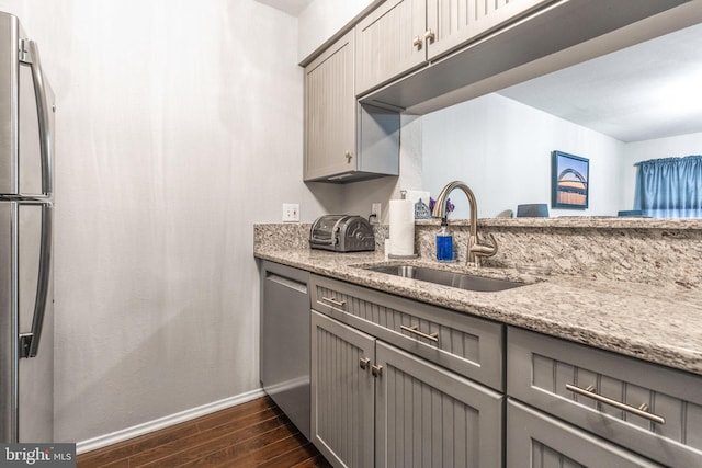 kitchen featuring light stone counters, sink, gray cabinets, and appliances with stainless steel finishes