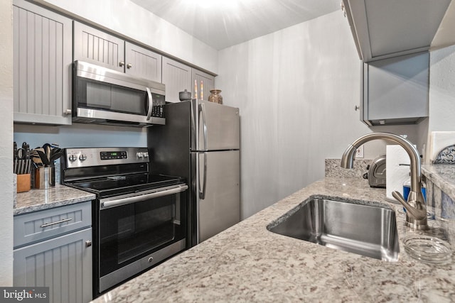 kitchen featuring appliances with stainless steel finishes, sink, and gray cabinetry