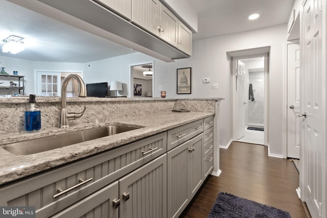 kitchen with dark wood-type flooring, light stone countertops, sink, and gray cabinetry