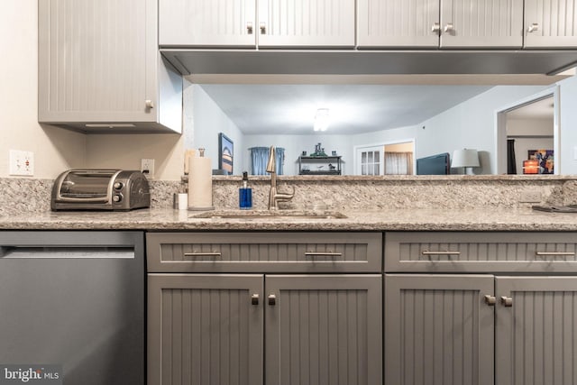 kitchen with light stone counters, gray cabinets, dishwasher, and sink