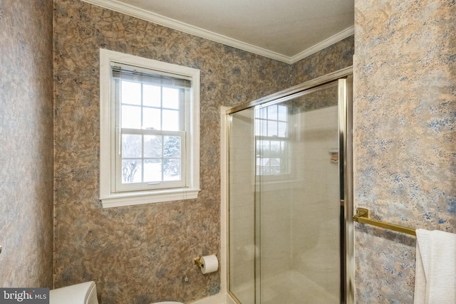 bathroom with ornamental molding, toilet, and a shower with shower door