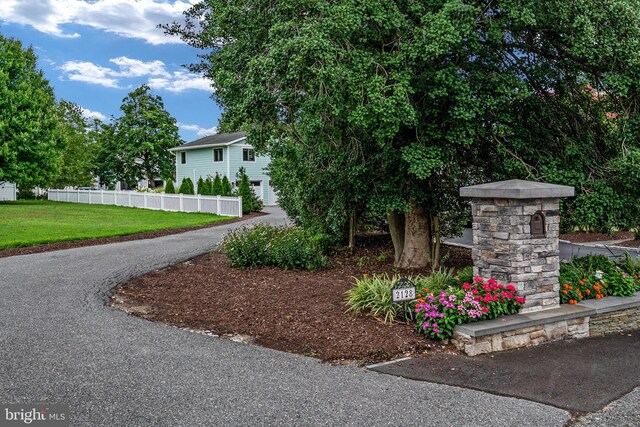 exterior space featuring aphalt driveway, a lawn, and fence