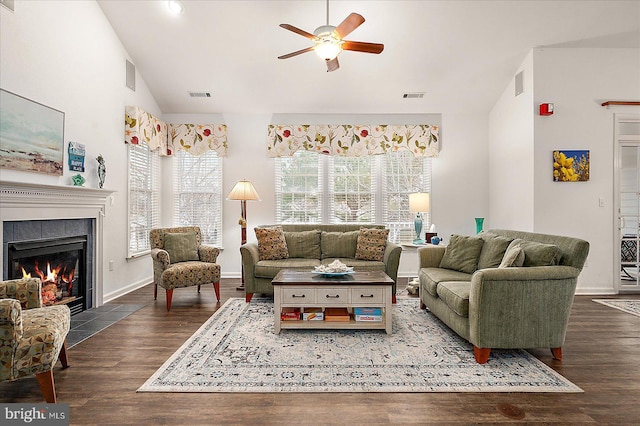 living room with a tiled fireplace, high vaulted ceiling, dark wood-type flooring, and ceiling fan