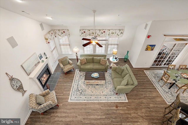 living room with dark hardwood / wood-style flooring, ceiling fan, a fireplace, and a healthy amount of sunlight